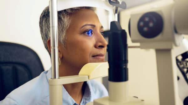 Máquina de teste oftalmológico e uma mulher madura realizando exame para detectar algum problema ocular