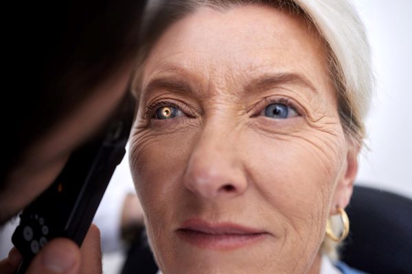 Linda mulher idosa sendo examinada por médico oftalmologista para identificação de catarata.