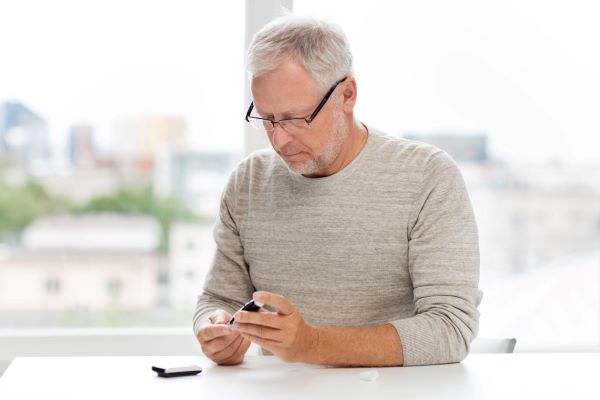 Senhor de meia idade fazendo o teste para verificar o índice glicêmico em razão de diabetes. Doença esta capaz de provocar retinopatia. 