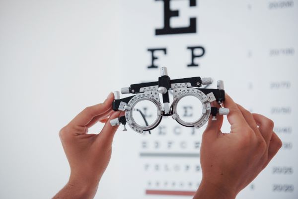 Mulher segurando um foróptero com as mãos - este é um instrumento utilizado em consultas para verificar o grau de lentes adequadas ao paciente.