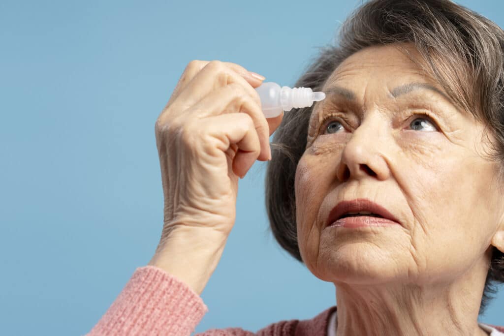 Uma idosa está pingando colírio para tratamento de doença ocular.