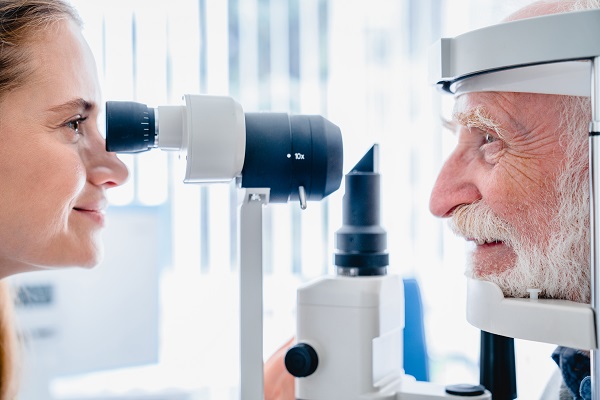 Oftalmologista realizando exame ocular em paciente idoso.