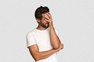 Jovem com cabelos e barba escuros, vestindo camiseta branca, demostra sinais de esquecimento de algo cobrindo o rosto com uma das mãos.