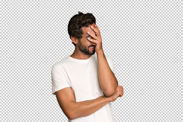 Jovem com cabelos e barba escuros, vestindo camiseta branca, demostra sinais de esquecimento de algo cobrindo o rosto com uma das mãos.