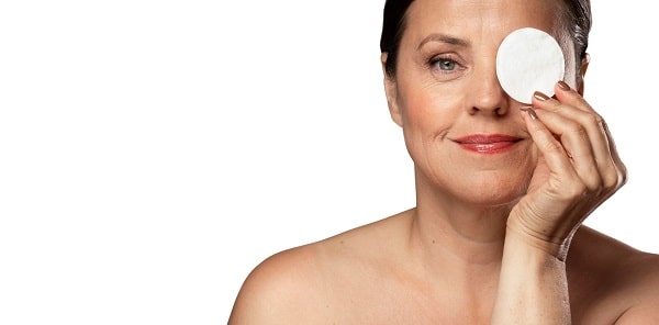 Mulher madura colocando compressas nos olhos. Este é um dos cuidados pós-cirúrgicos essenciais na fase imediata.