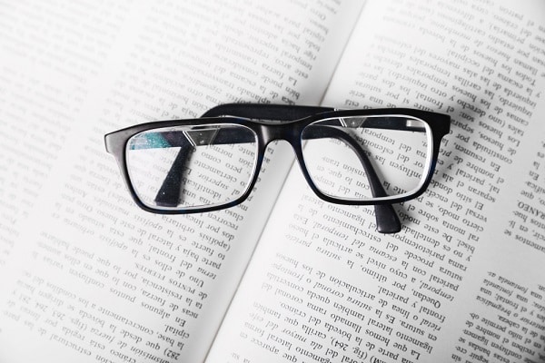Um par de óculos de grau, preto, está sobre páginas de uma livro aberto.
Presbiopia é uma das doenças oculares que costuma ser comum nessa fase dos 50 anos.